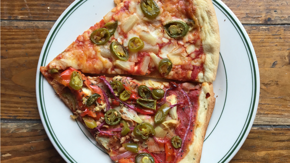 Two slices of pizza on a plate with various toppings, including cheese and peppers
