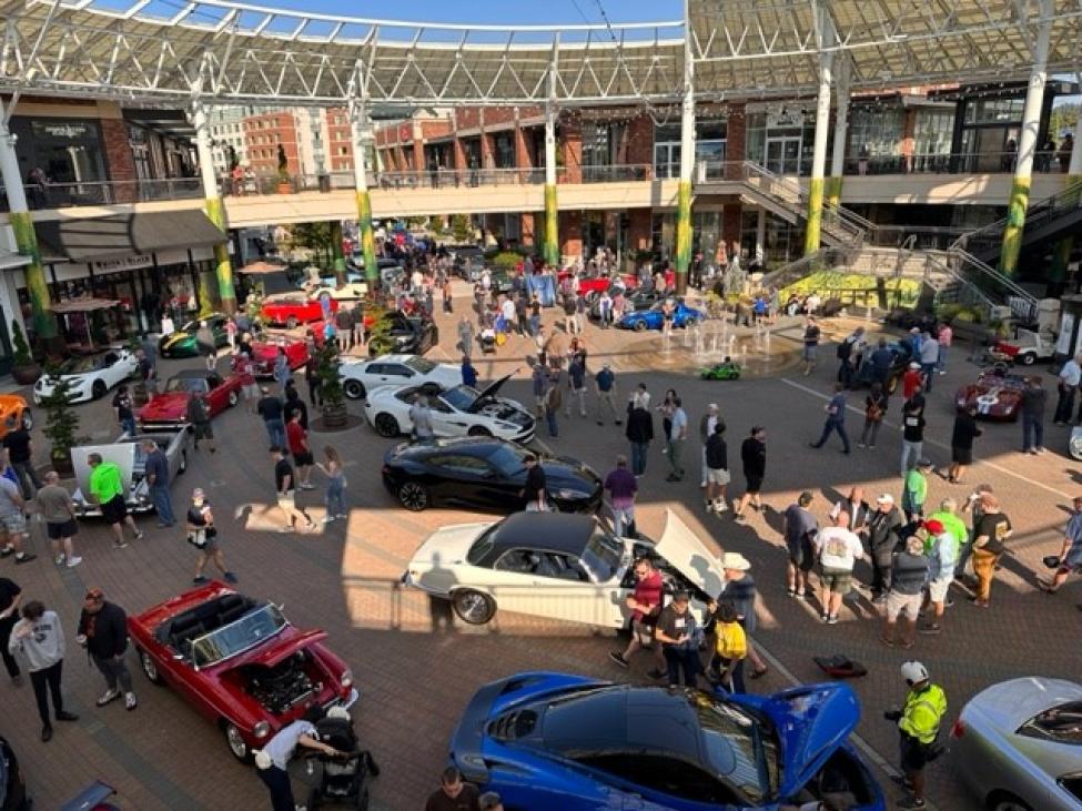 A group of people walk around sports cars on display at the plaza of Redmond Town Center