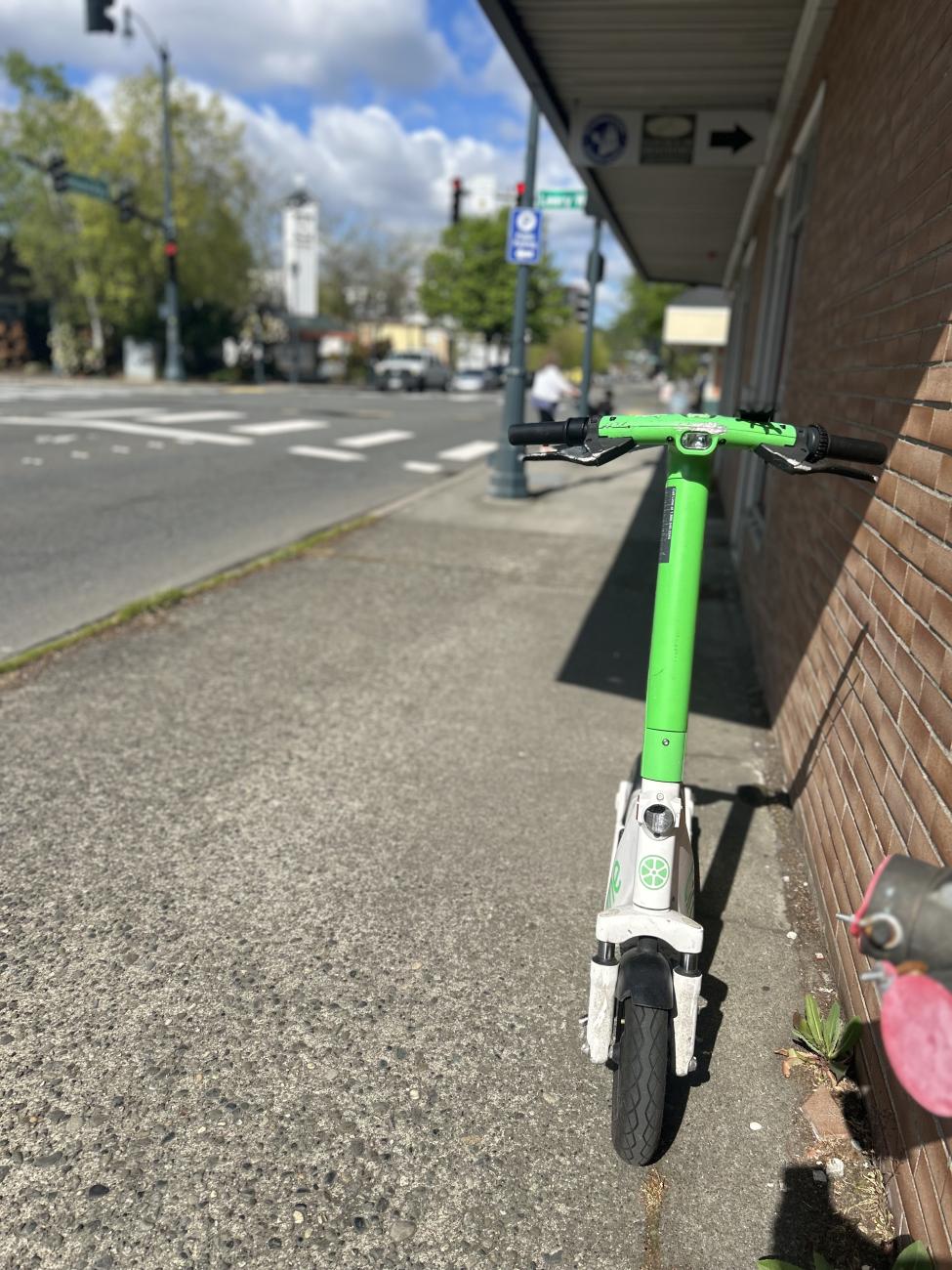 Head on shot of a Lime scooter parked in front of some small businesses