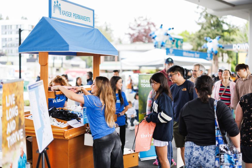 A crowd of people engage with a Kaiser Permanente pop up cart at the Downtown Redmond opening
