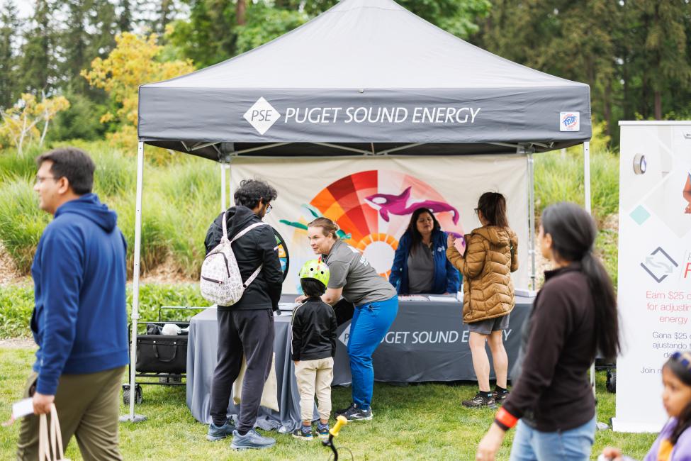 Puget Sound Energy staff greet passengers at their table.
