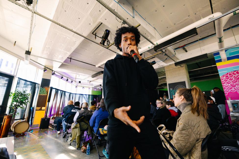 A performer looks into the camera as he performs into the mic.