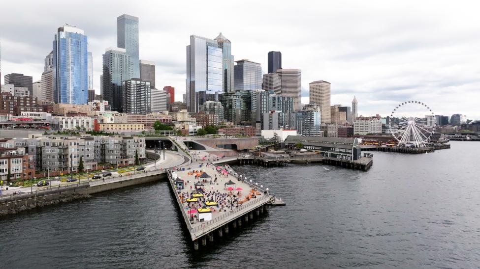 A drone shot of Pier 62 with the Seattle skyline, including the Great Wheel, in the background.