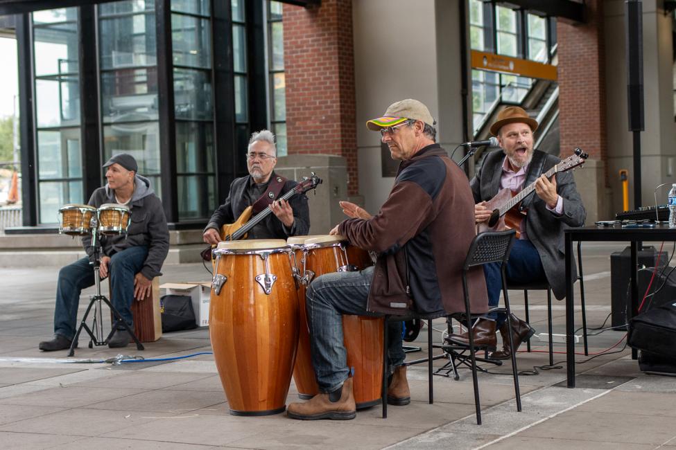 A group of musicians playing guitars and bongo drums play at Mount Baker Station