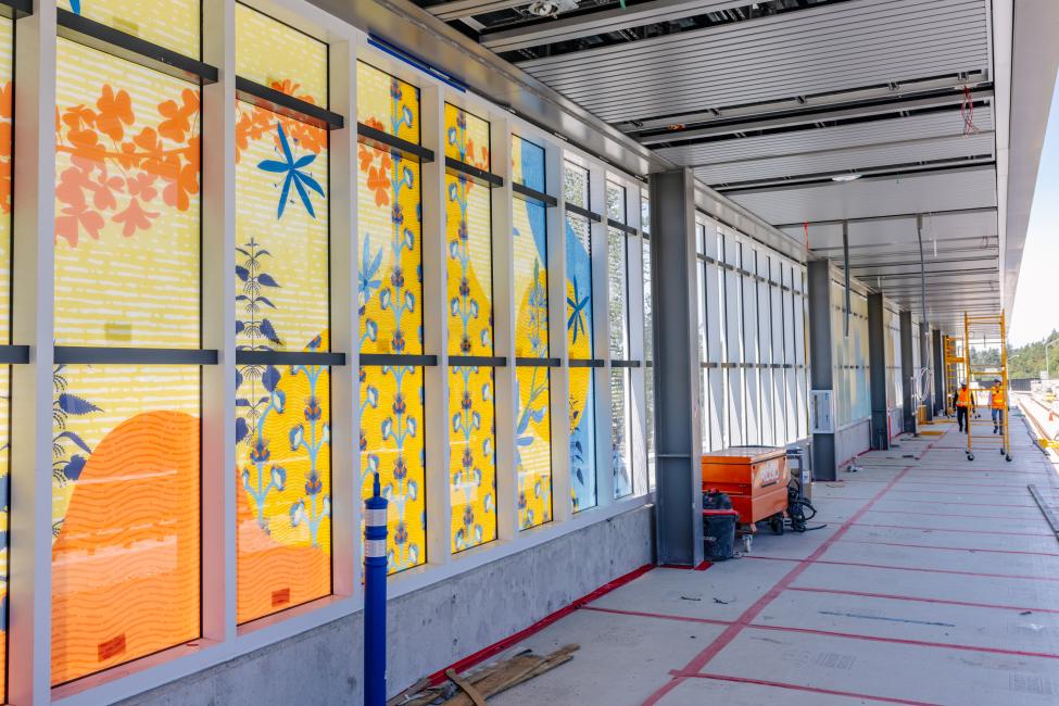 A yellow, orange, and blue glass mural at a light rail station