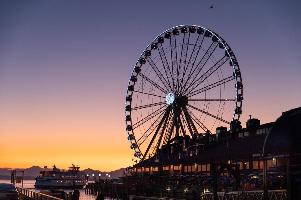 The dark outline of Seattle's Great Wheel against an orange and purple sky