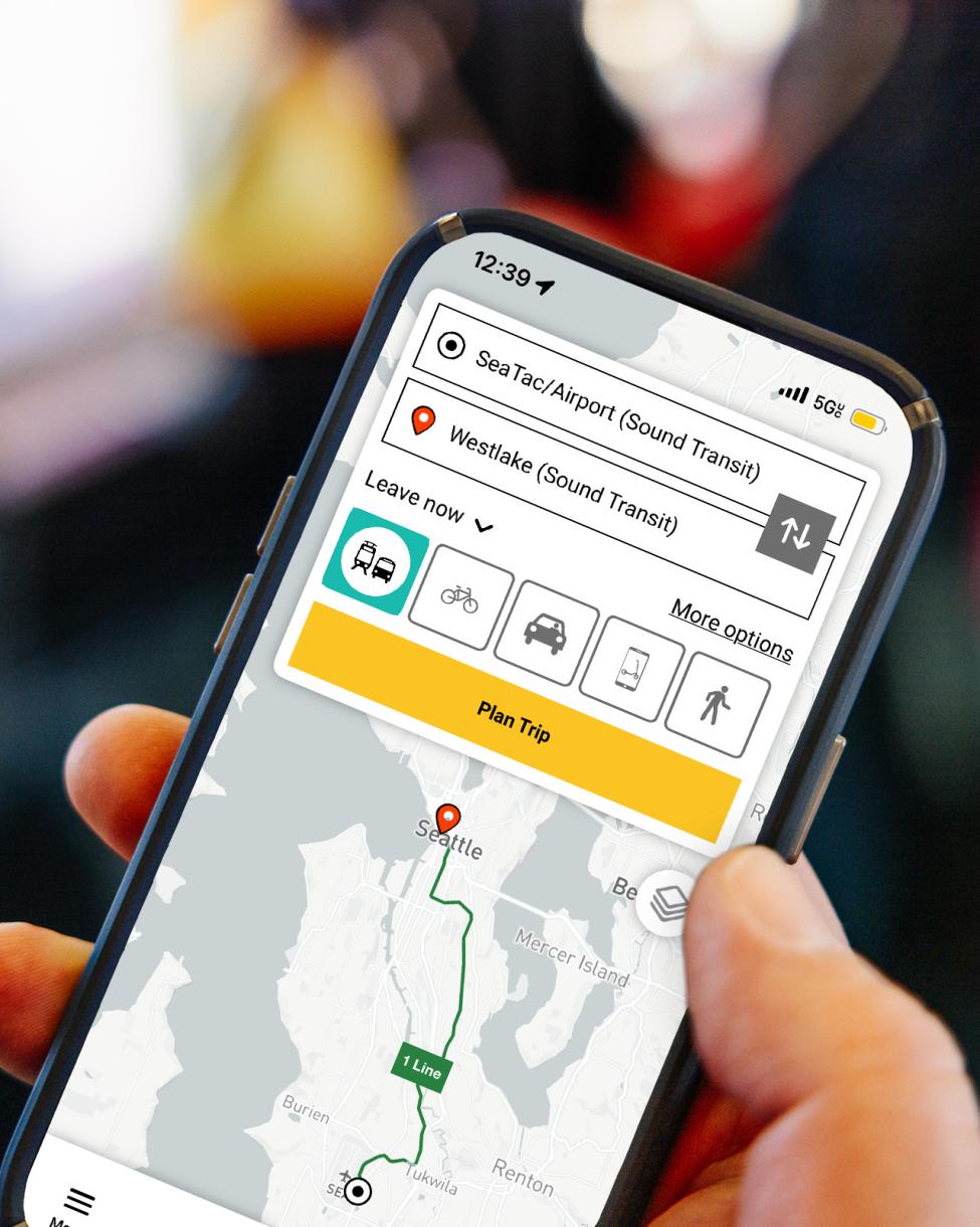 A hand holds a phone showing the new Sound RideGuide trip planner