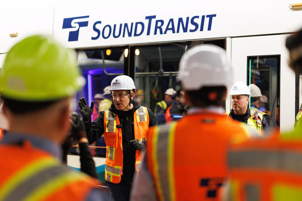Dow Constantine wears a hard hat and orange vest while speaking to crews before the train testing begins
