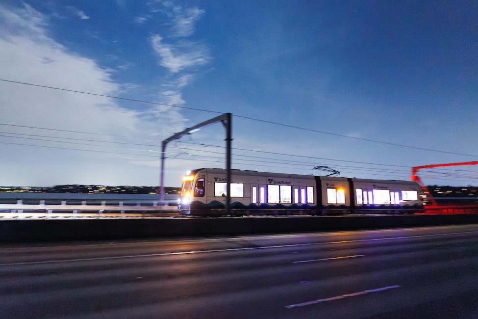 Dark blue sky behind a lit up Link light rail train while crossing the I-90 floating bridge.