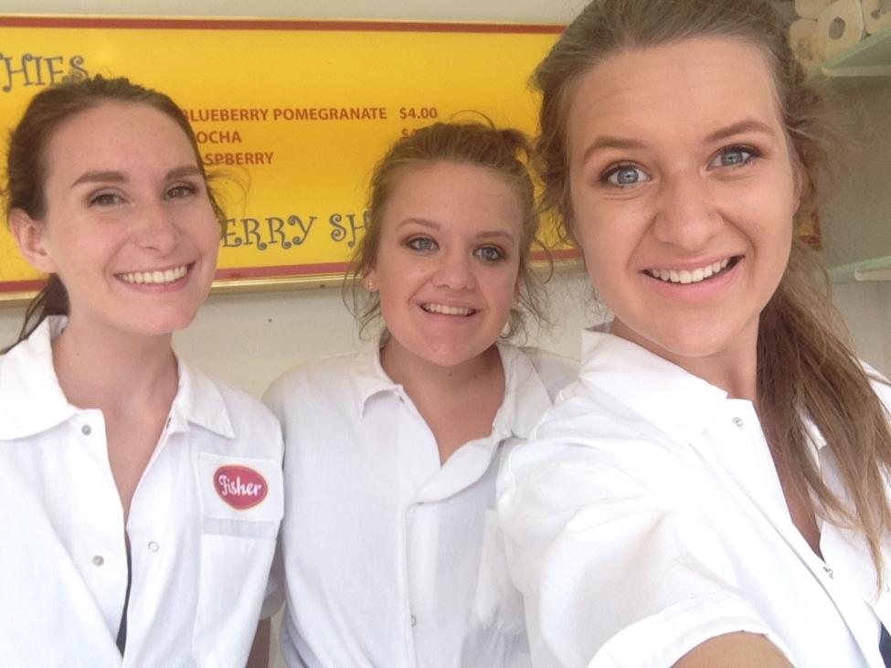 Three women in white shirts smile at the camera