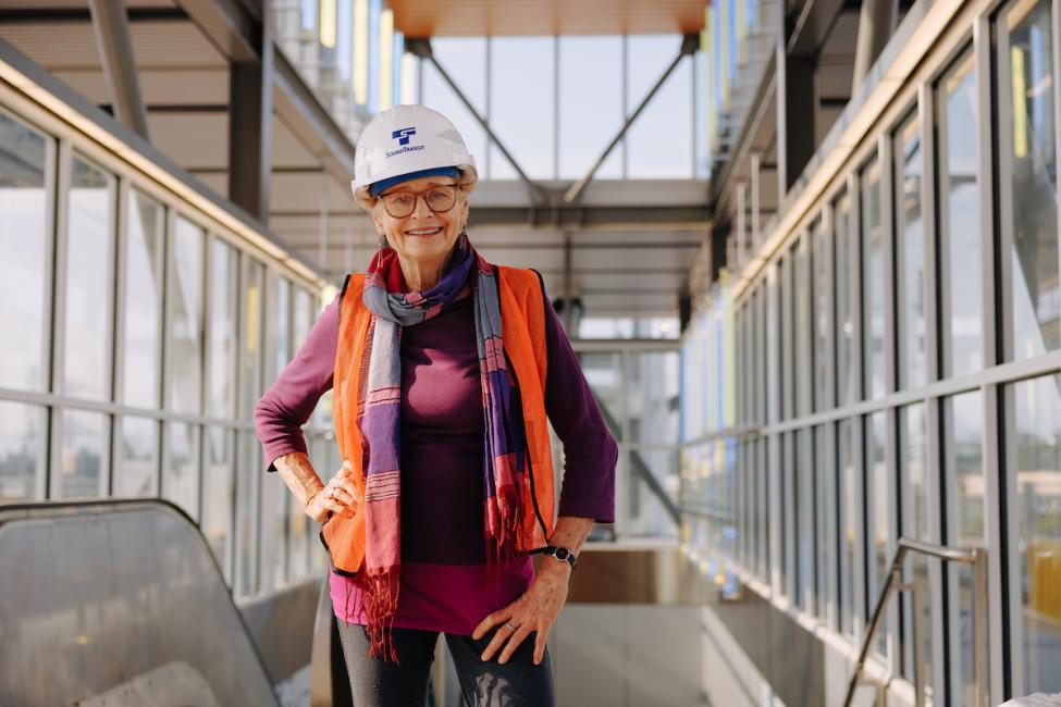 Catherine Widgery, wearing an orange coat and hard hat, smiles at the camera