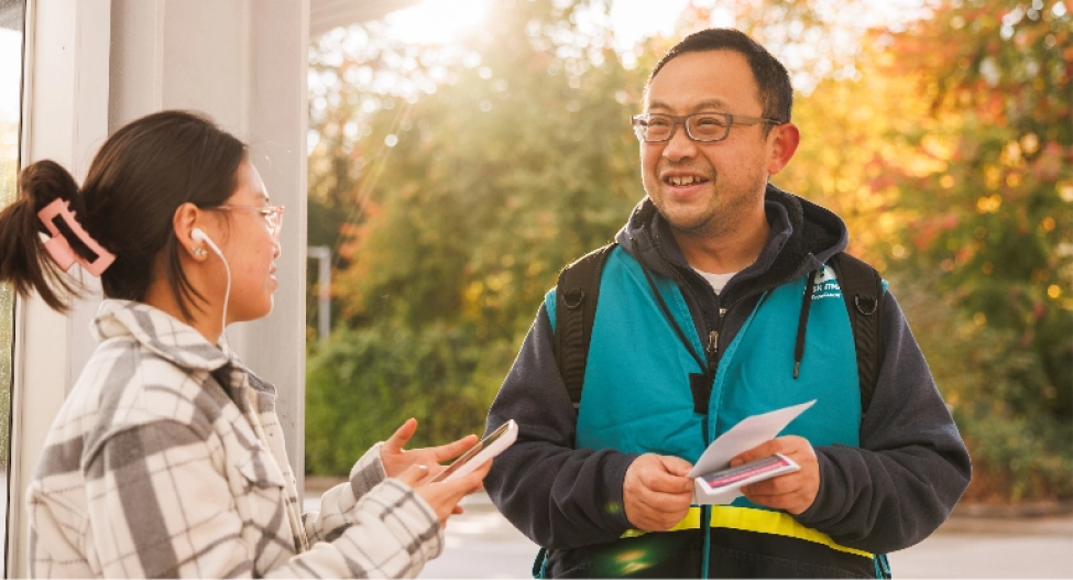 A Sound Transit employee wearing an ambassador vest speaks to a passenger.