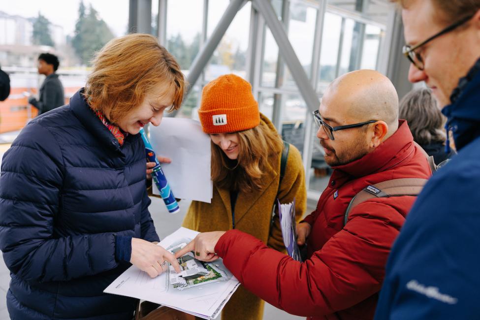 Four Sound Transit employees review a document at a light rail station