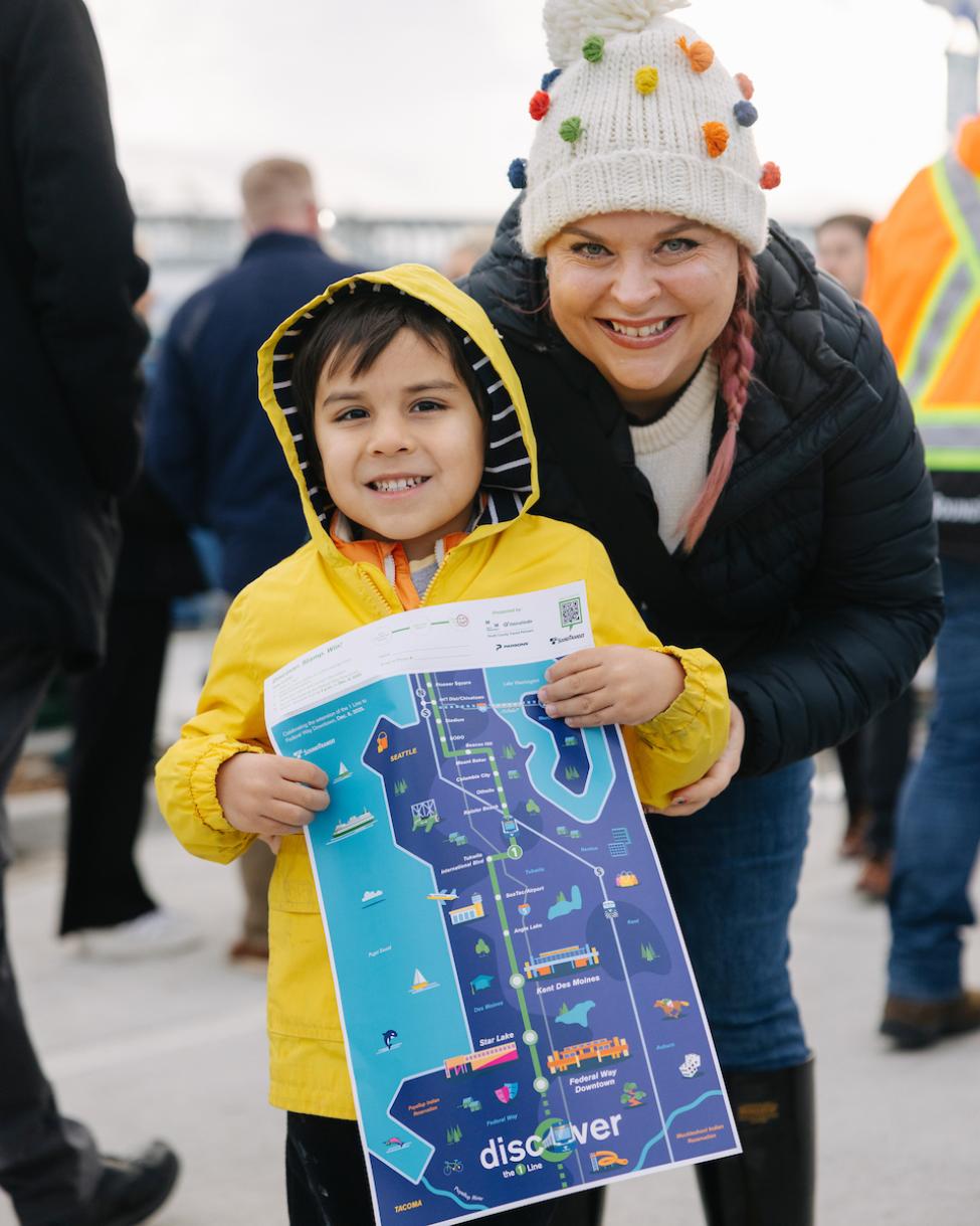 A child and adult hold up a commemorative map