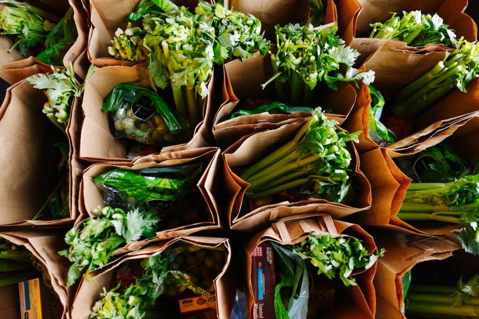 Overhead view of leafy greens in a brown paper bag.