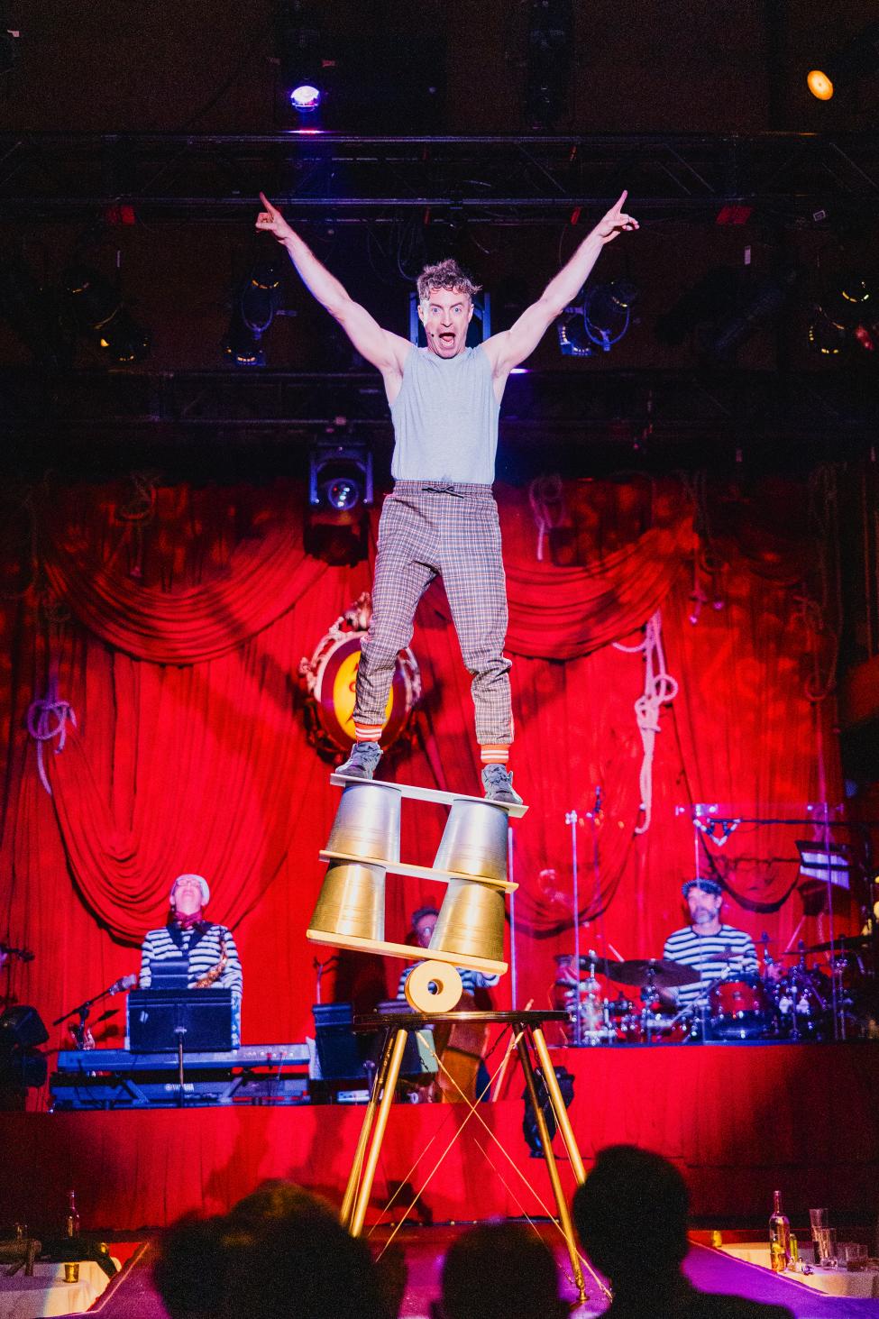 A performer balances acrobatically while pointing enthusiastically in the air.