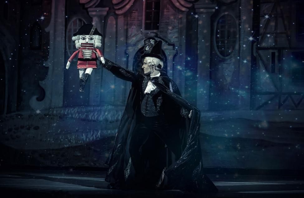 A promotional image for the nutcracker with a victorian man holding up a traditional nutcracker