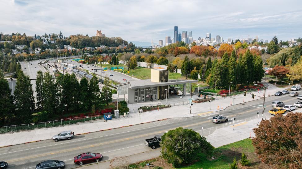 An entrance to Judkins Park Station features art of Jimi Hendrix. I-90 is in the immediate background, with the downtown Seattle skyline further back.