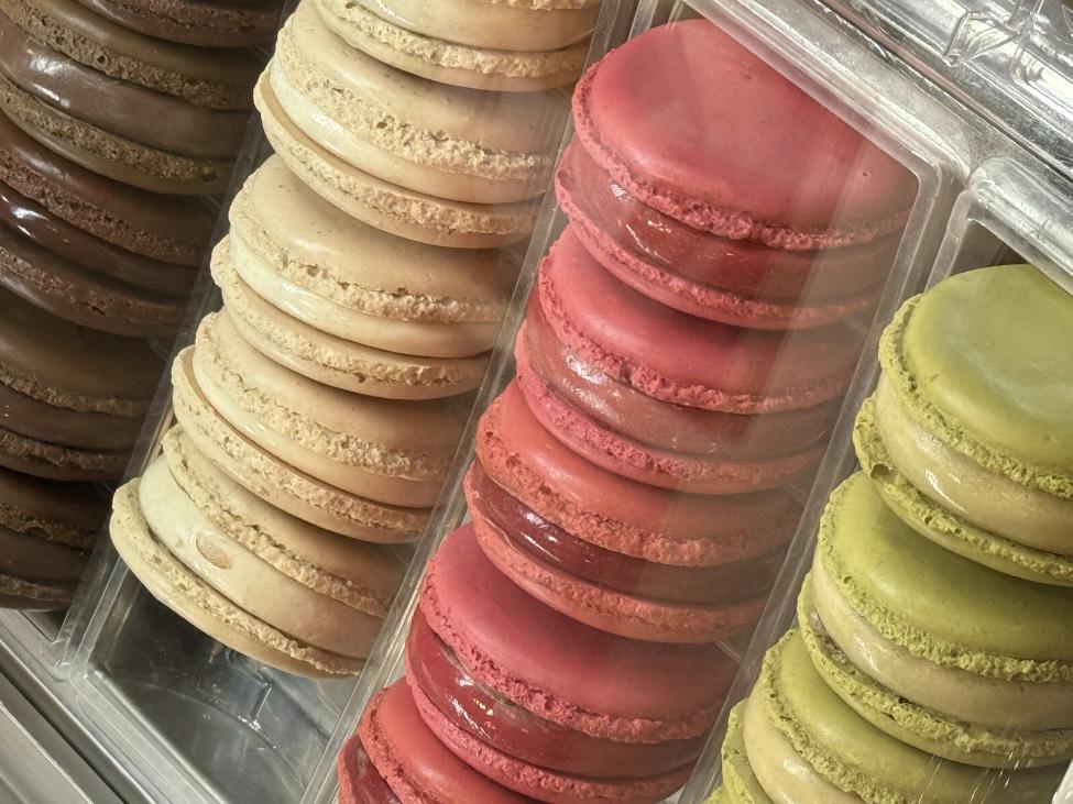 Rows of brown, white, pink, and green macarons