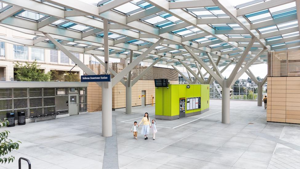 A mom and two kids hold holds walking through the plaza at the light rail station in downtown Bellevue
