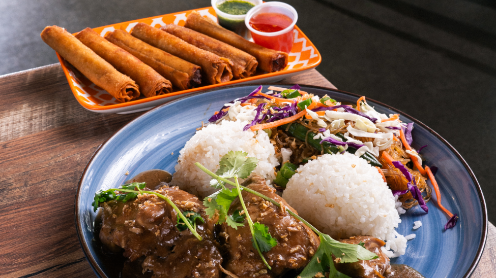 A rice dish with a fried rolled appetizer behind it