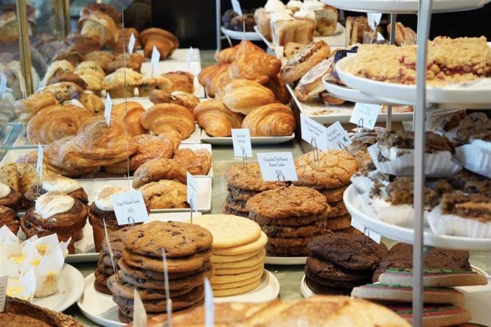 A display case in a bakery with dozens of cookies and other baked goods