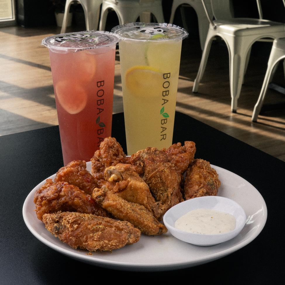 A plate of chicken with two brightly colored drinks behind it
