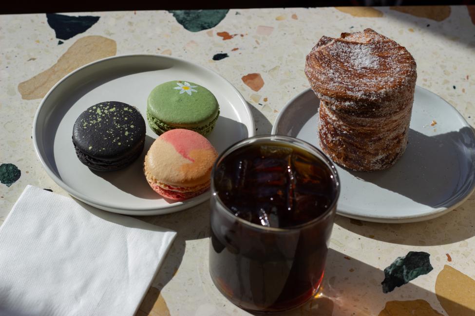 A plate of macaroons and two iced coffee drinks on a table