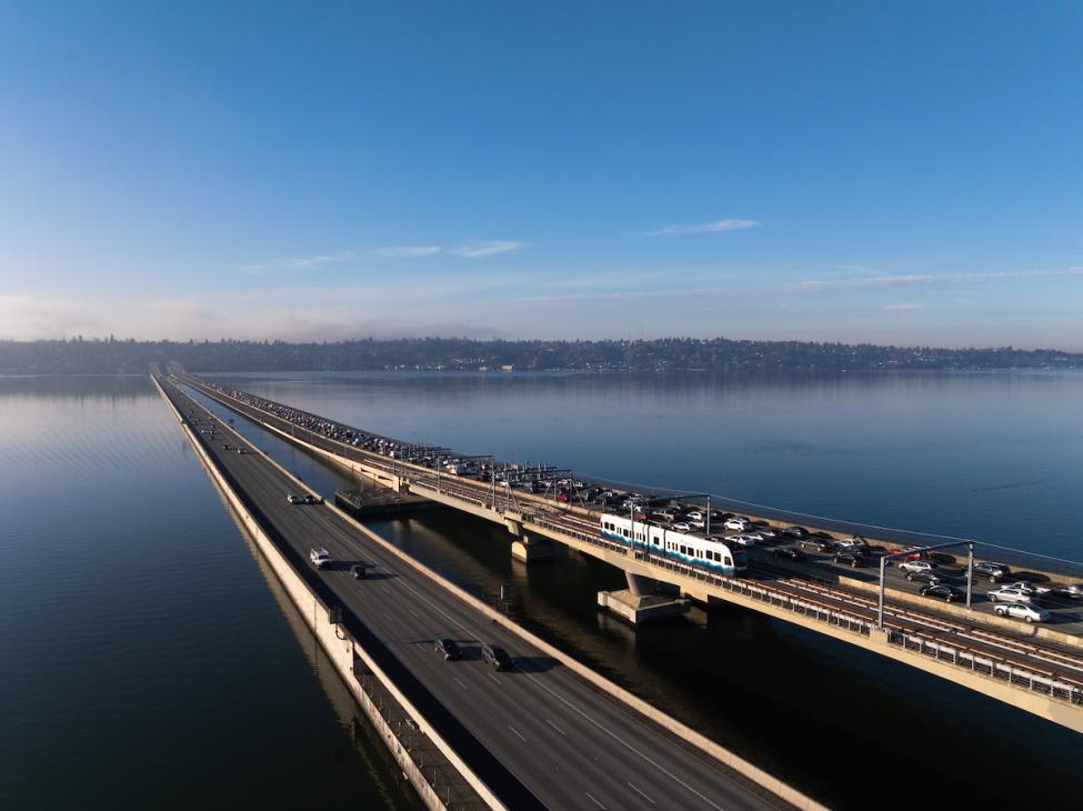 A drone photograph of a link light rail vehicle riding on the floating bridge