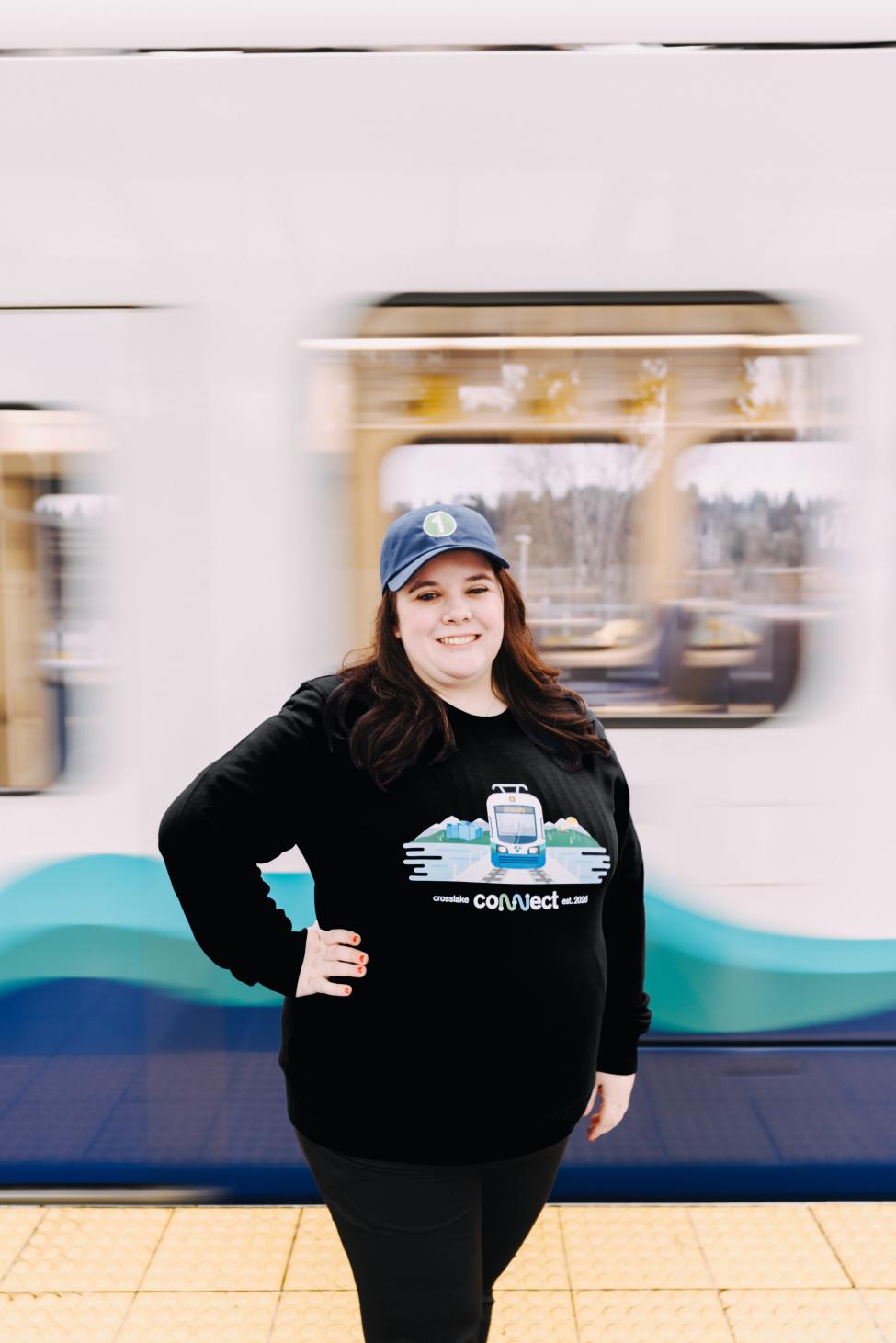 A woman stands in front of a train with Crosslake merchandise on