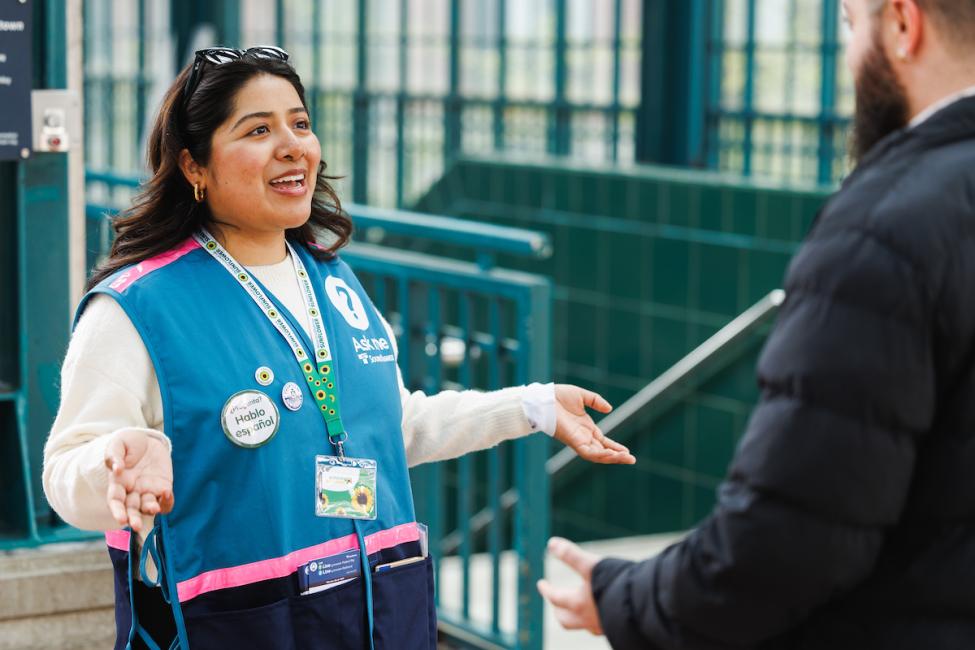 Staff Ambassador Abbi wears a teal vest and helps a passenger at International District Station