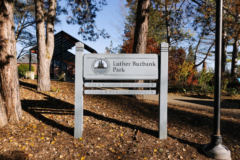 A sign for Luther Burbank park with trees and a blue sky in the background