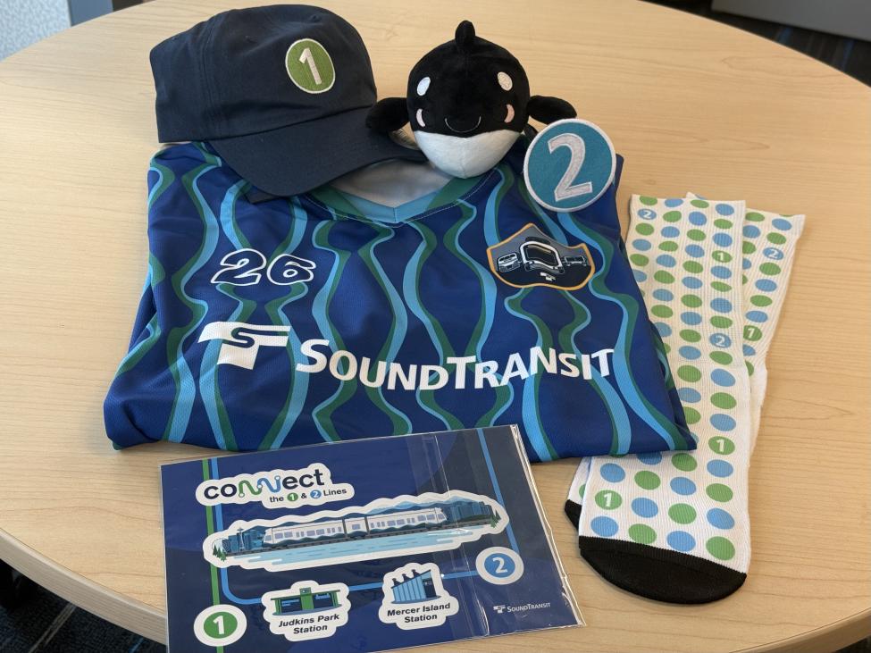 A jersey, hat, sticker pack, socks, and a Boop plushie on a table