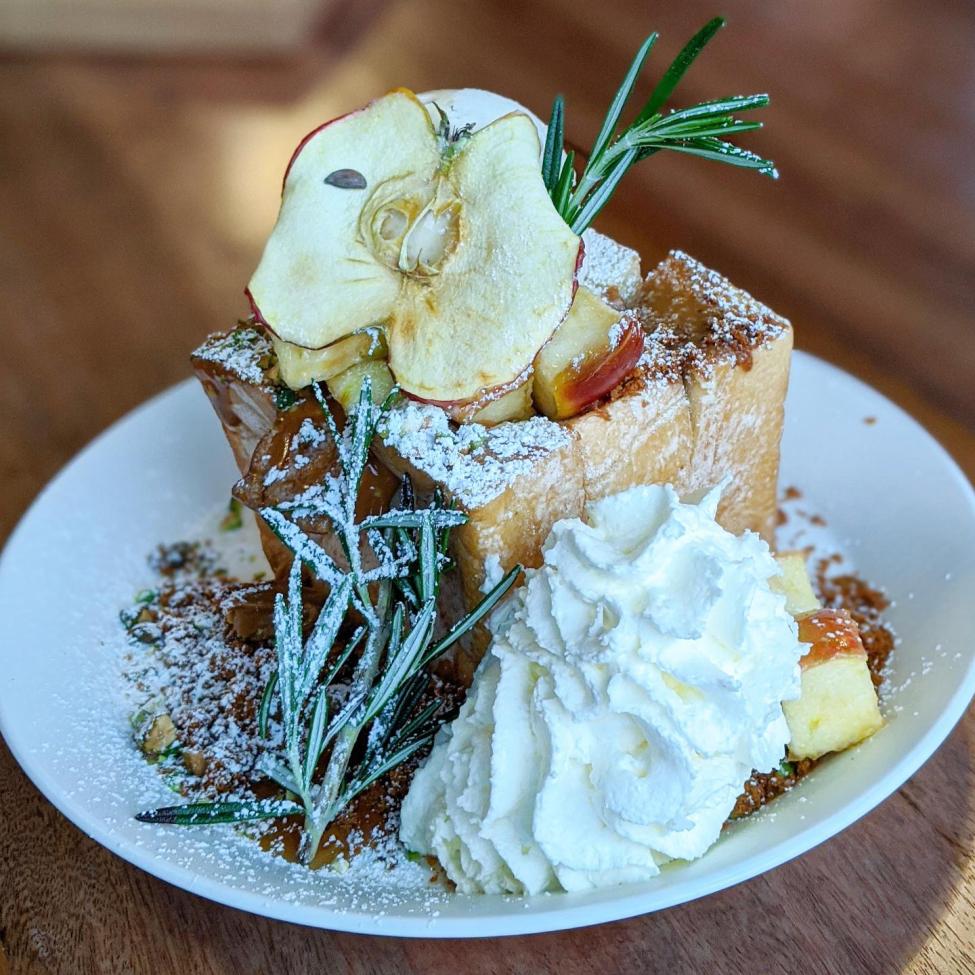 A decadent dessert with a dried apple on top and whipped cream on the side
