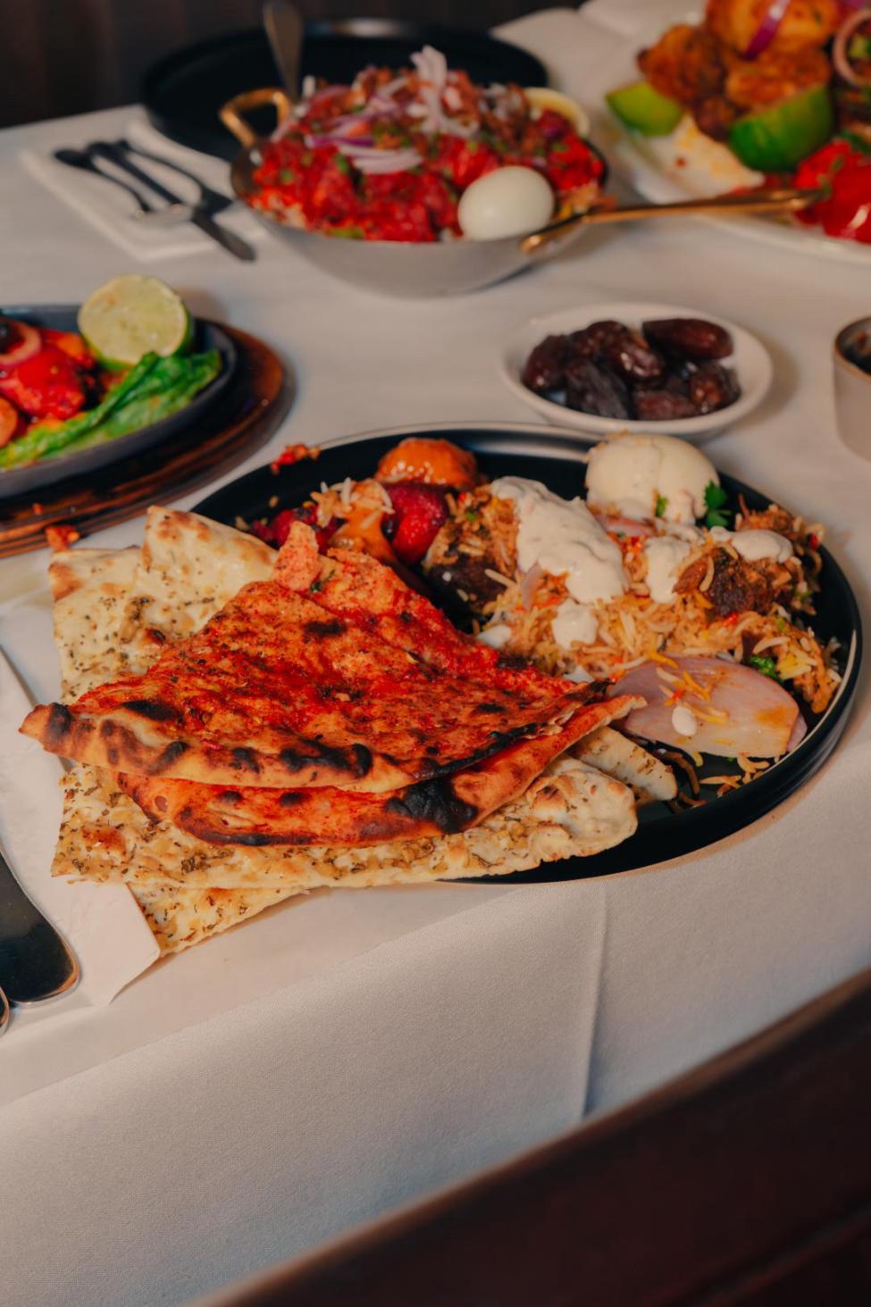 A table with a white tablecloth and four Indian dishes on top