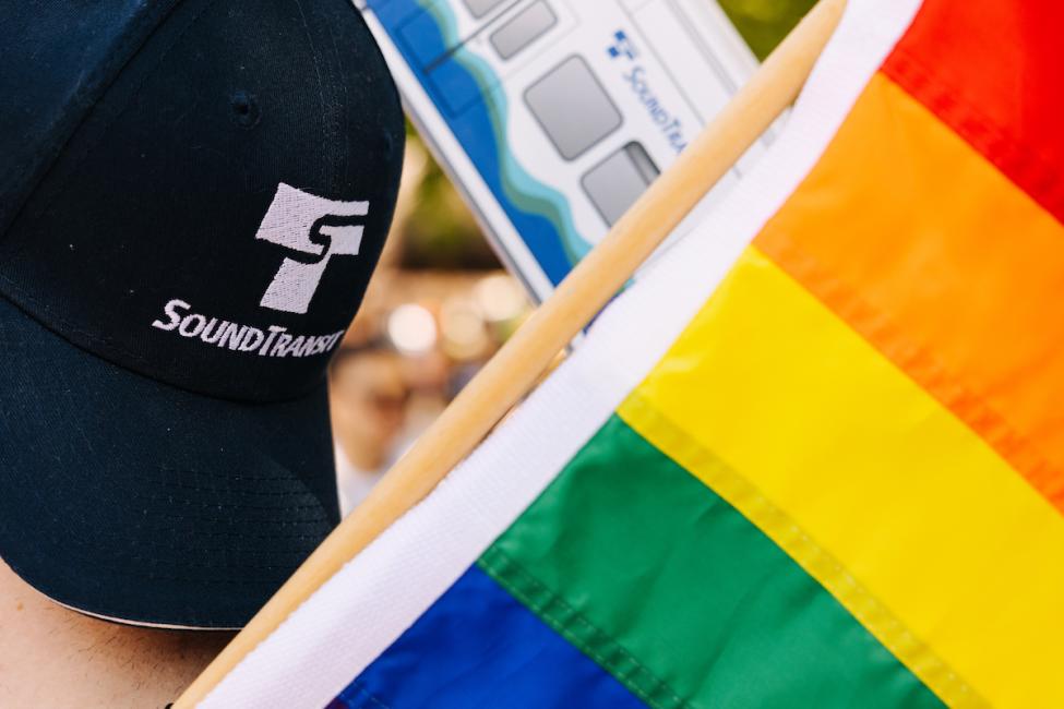 A blue hat with a Sound Transit logo is next to a rainbow flag