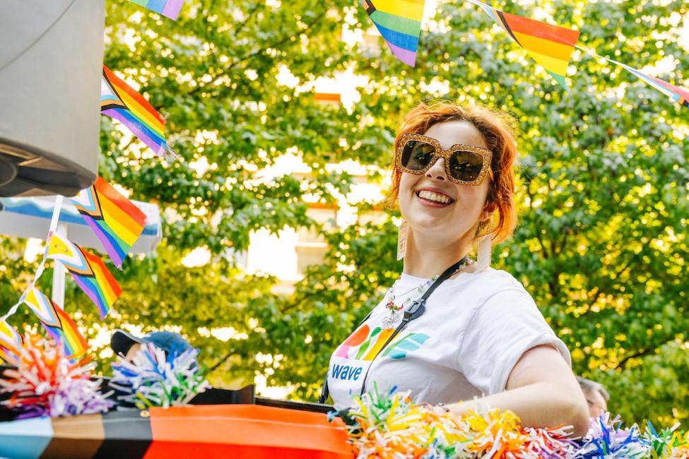 A Sound Transit employee rides in a Pride Parade float on a sunny day