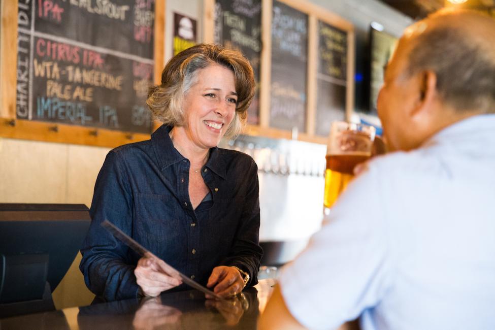 An employee at Bellevue Brewing leans over the counter to talk to a customer
