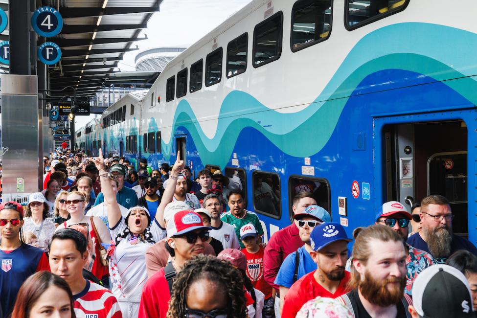 A large group of soccer fans head from King Street Sounder station to the match, with one person in the crowd exuberantly cheering