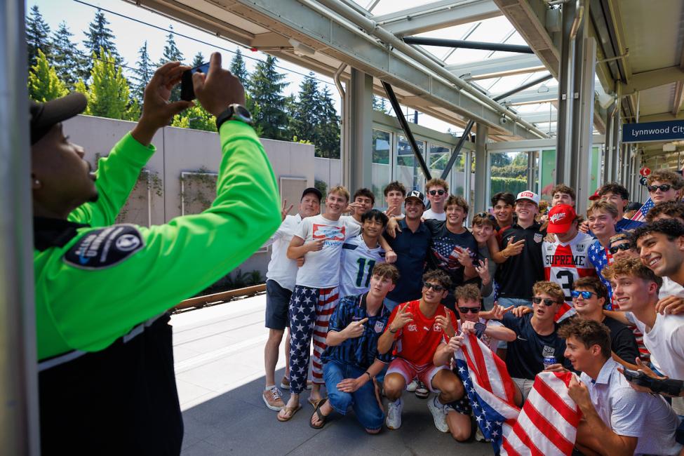 A security officer takes a photo of a large group of soccer fans at a Link station
