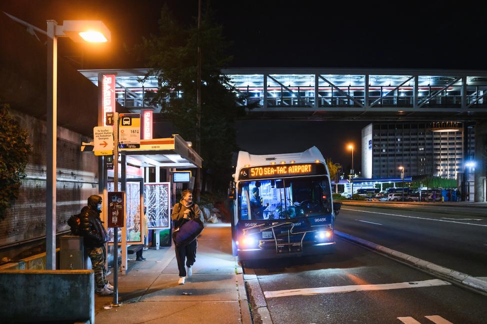 People wait at a stop for ST Express bus 570, which provided overnight service as part of a pilot in 2026.