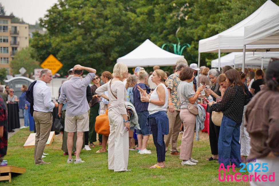 A group of people mingle among booths at Mercer Island's art event