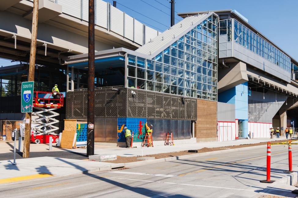 Looking at Pinehurst Station from across the street, workers can be seen installing art at the street level