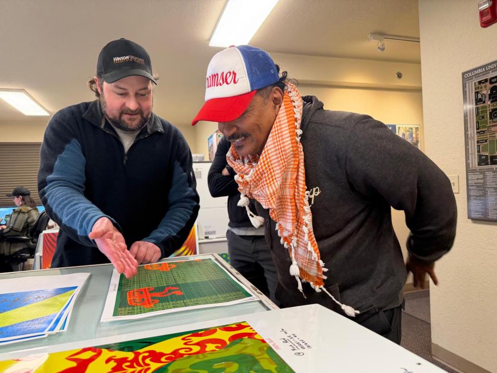 Two people look at art concepts laid out on a table