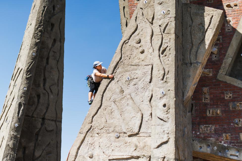 A person perches on the climbing rock at Marymoor Park on a sunny day