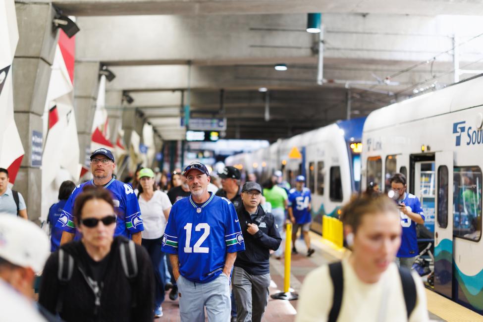 People wearing Seahawks jerseys walk toward the exit at International District Chinatown Station 