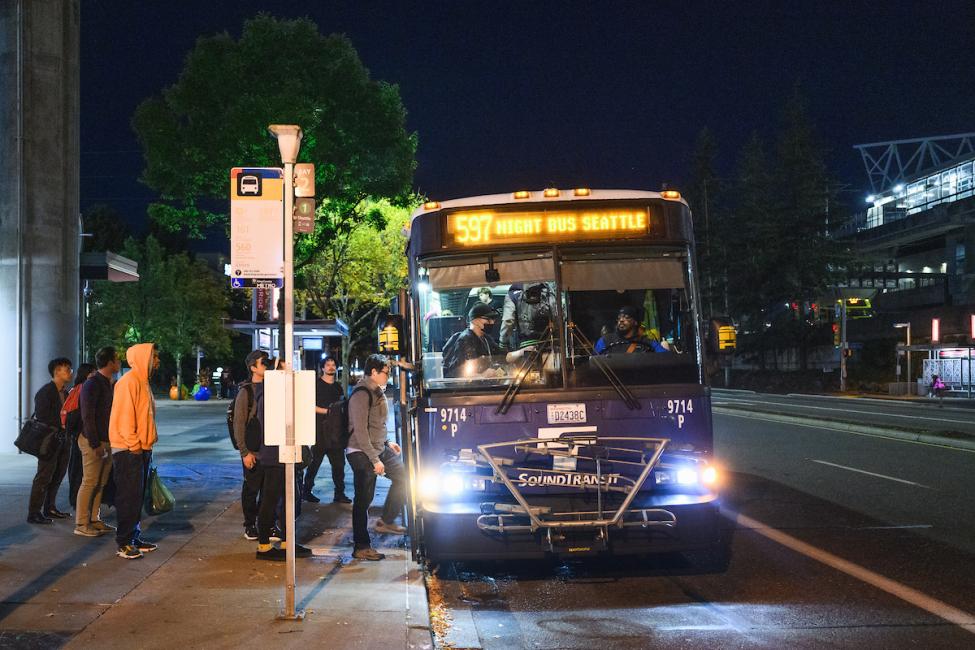 Riders board a Route 597 bus at night at SEA Airport.