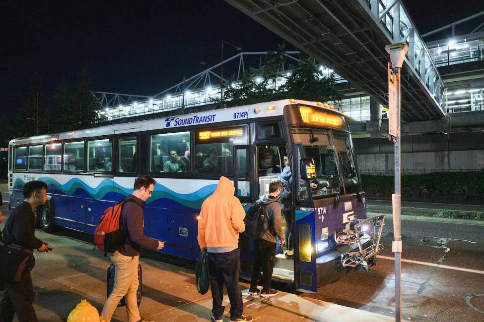 Riders board a Route 597 bus at night, during the hours Link light rail is not running.