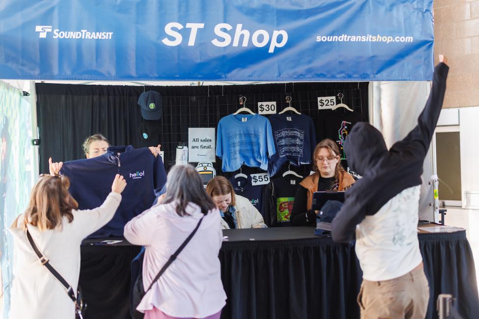 A group of passengers wait in line at the pop-up ST Shop tent