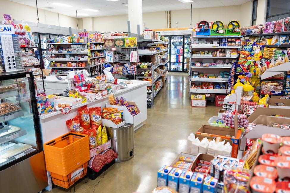 A brightly lit grocery store, with the checkout area on the left and shelves on the right